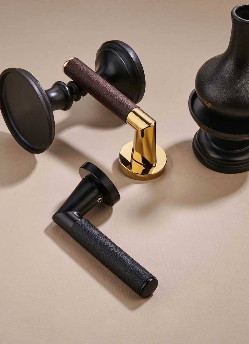 Premium interior door levers by KMAN SMART featuring hand-wrapped lychee-grain leather in dark brown and black, paired with mirror gold and matte black metal finishes.